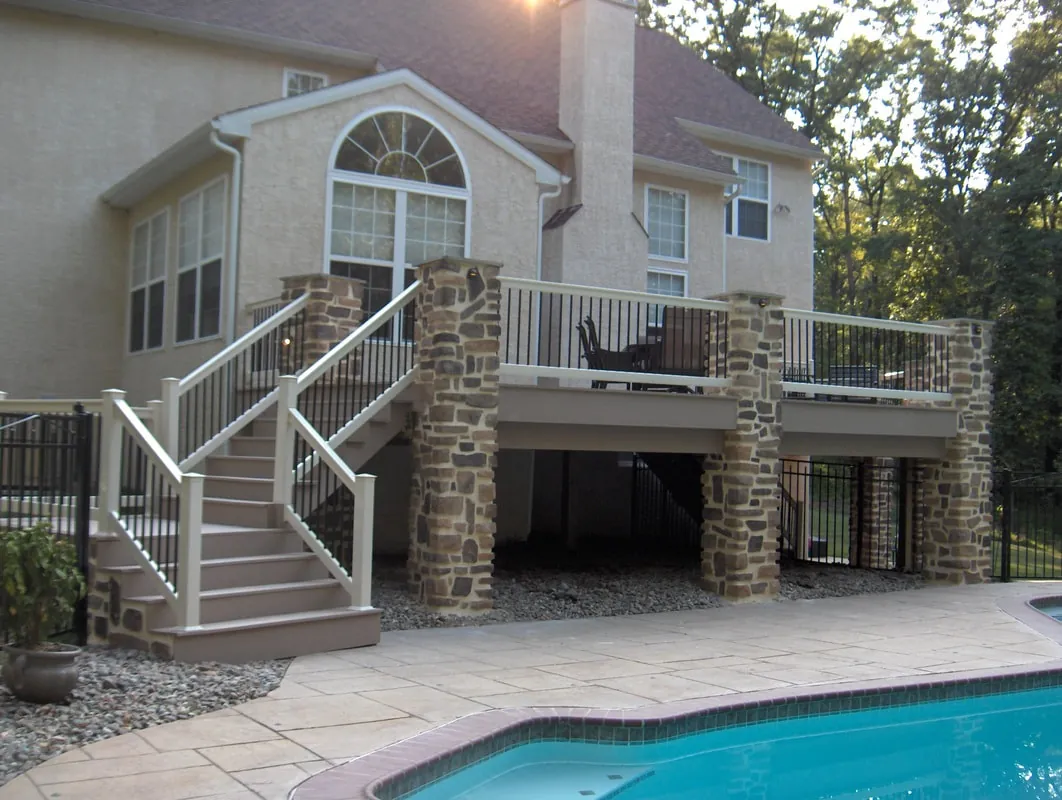 Raised rear deck with stone columns and stairs above a pool