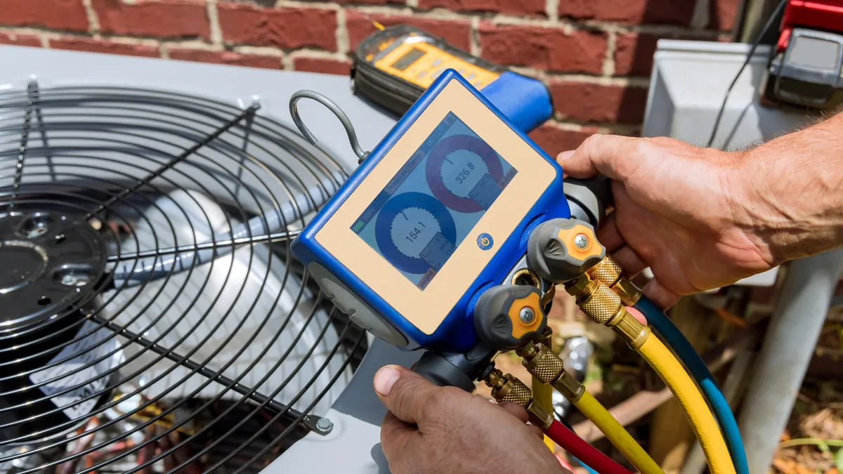 Technician testing air conditioner refrigerant pressure